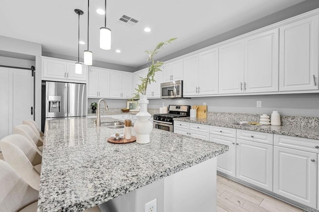 kitchen with white cabinetry, appliances with stainless steel finishes, visible vents, and a sink