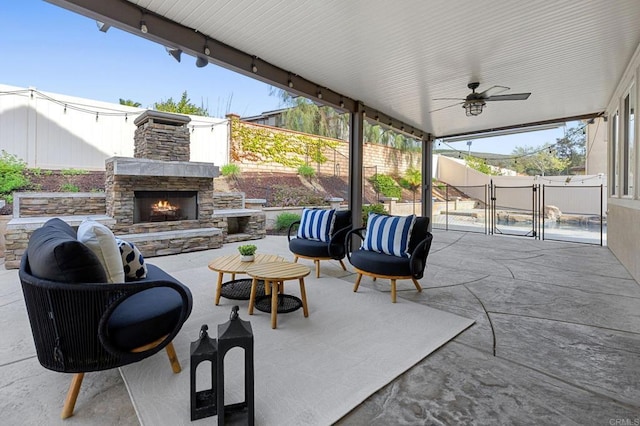 view of patio / terrace with an outdoor living space with a fireplace, ceiling fan, and a fenced backyard