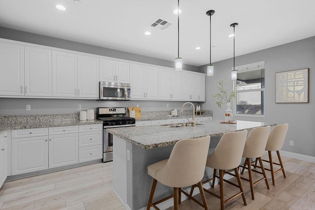 kitchen featuring light wood-type flooring, appliances with stainless steel finishes, visible vents, and a sink