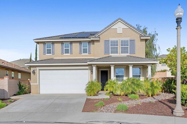 traditional-style home with fence, solar panels, an attached garage, stucco siding, and concrete driveway