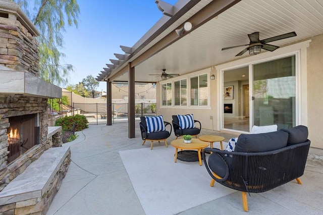 view of patio featuring a ceiling fan, an outdoor living space with a fireplace, and fence