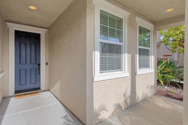view of exterior entry featuring stucco siding and covered porch