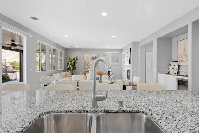 kitchen featuring plenty of natural light, visible vents, light stone counters, and a sink