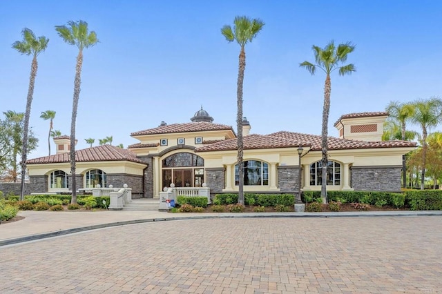 view of front of home with stone siding, a tiled roof, and stucco siding