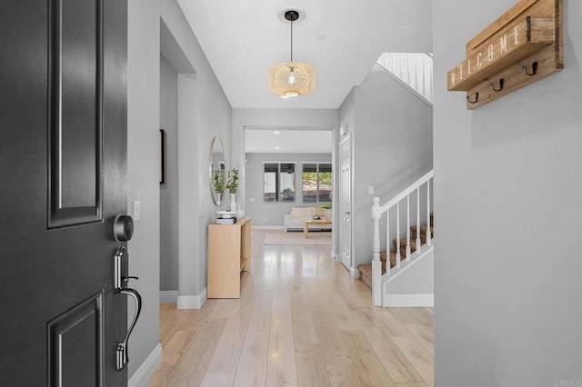 entryway with stairs, baseboards, and light wood-style flooring