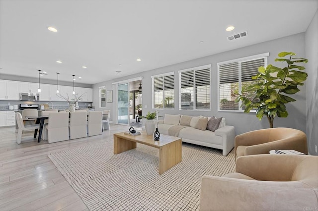 living room featuring light wood finished floors, visible vents, and recessed lighting