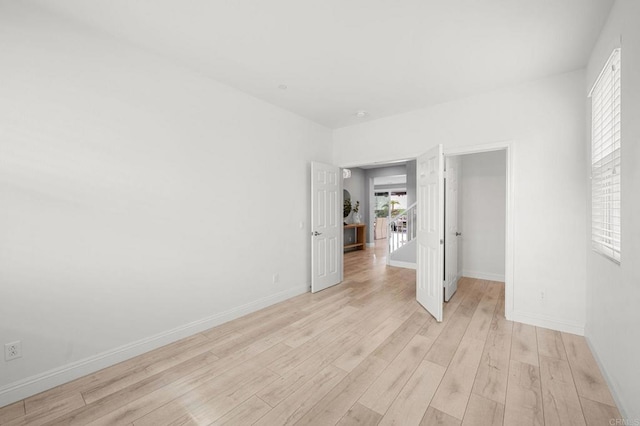 unfurnished room with baseboards, a healthy amount of sunlight, and light wood-style flooring