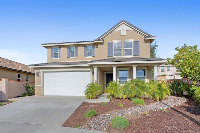 traditional home with driveway, fence, covered porch, a garage, and stucco siding