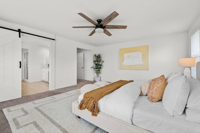 bedroom featuring a barn door, ceiling fan, visible vents, connected bathroom, and light colored carpet