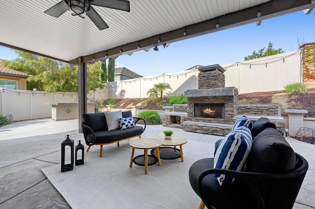 view of patio with an outdoor living space with a fireplace, a ceiling fan, and a fenced backyard