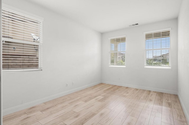unfurnished room featuring baseboards, visible vents, and wood finished floors