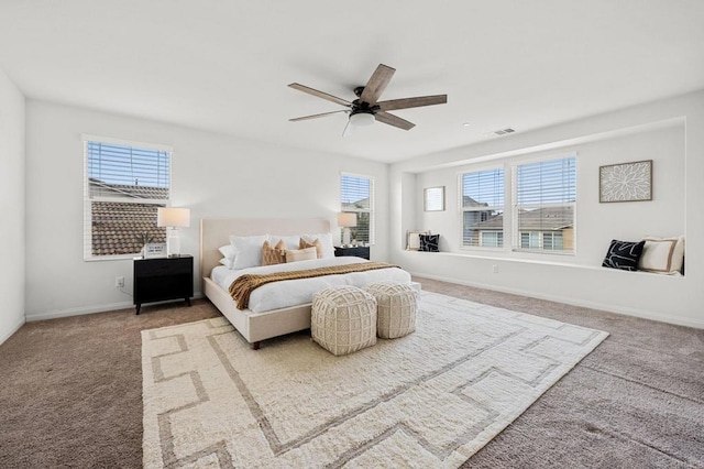 bedroom with ceiling fan, carpet floors, baseboards, and multiple windows