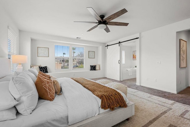 bedroom with ensuite bathroom, a barn door, visible vents, carpet flooring, and baseboards