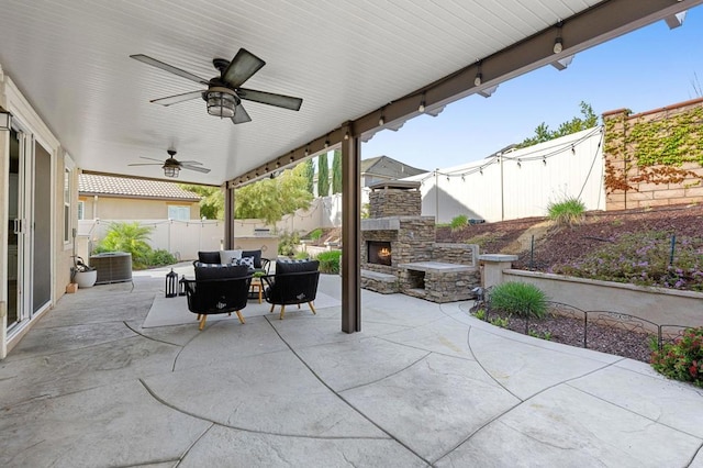 view of patio with a fenced backyard, ceiling fan, an outdoor living space with a fireplace, and cooling unit