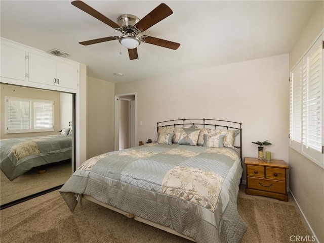 carpeted bedroom with a closet, baseboards, ceiling fan, and visible vents