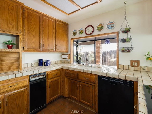 kitchen with dark tile patterned flooring, a sink, brown cabinetry, and dishwasher