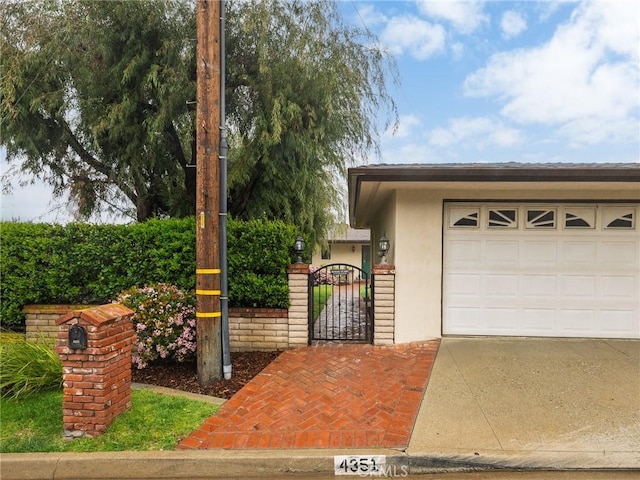 view of front of home with a garage, a gate, driveway, and stucco siding