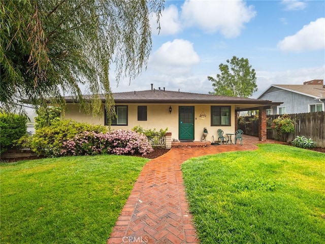 view of front of house featuring stucco siding, fence, and a front lawn