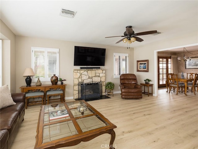 living area featuring ceiling fan with notable chandelier, visible vents, wood finished floors, and a fireplace