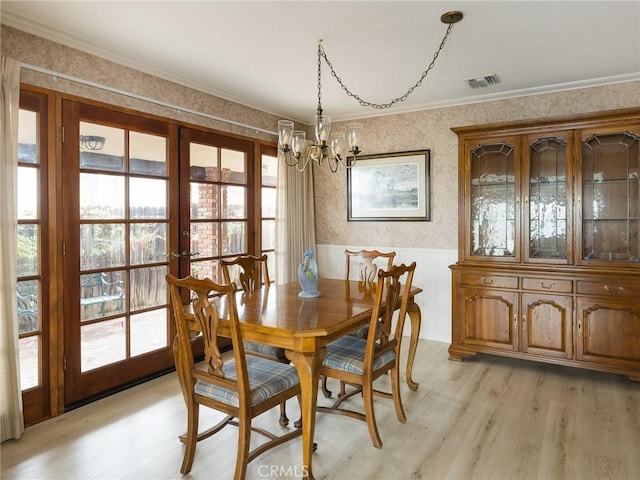 dining space featuring ornamental molding, visible vents, a notable chandelier, and wallpapered walls