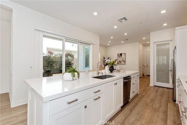 kitchen featuring light wood-style floors, a sink, white cabinets, and recessed lighting