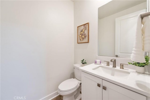 half bathroom featuring vanity, baseboards, and toilet