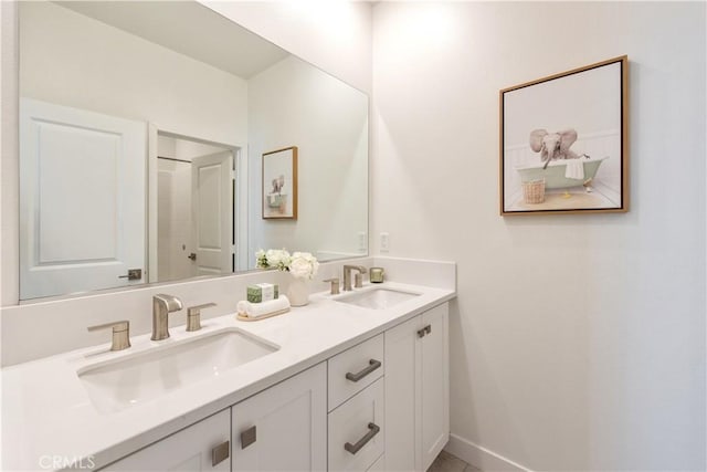 bathroom with double vanity, baseboards, and a sink