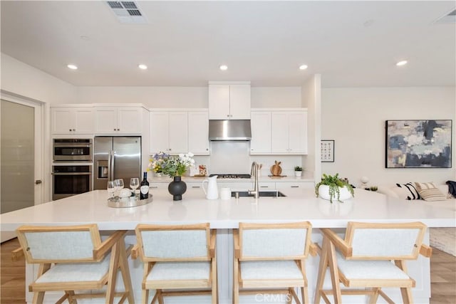 kitchen with visible vents, white cabinets, a sink, appliances with stainless steel finishes, and under cabinet range hood