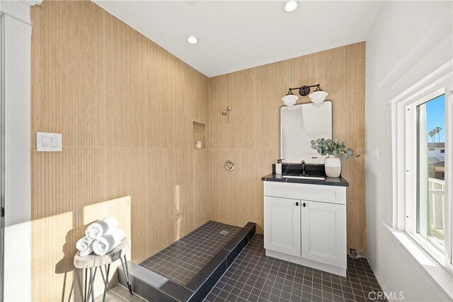bathroom with tile patterned floors, tiled shower, vanity, tile walls, and recessed lighting