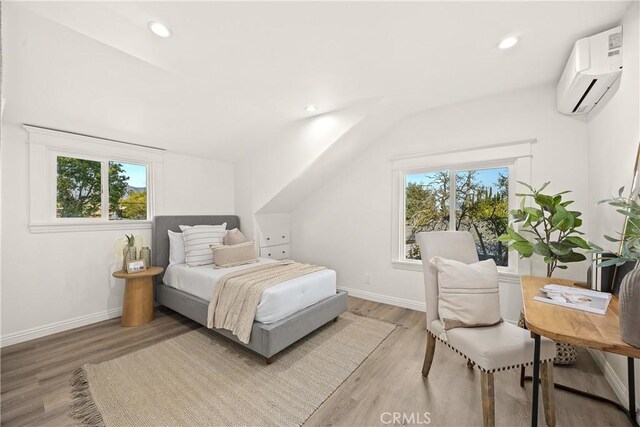 bedroom featuring light wood-style flooring, an AC wall unit, baseboards, recessed lighting, and lofted ceiling