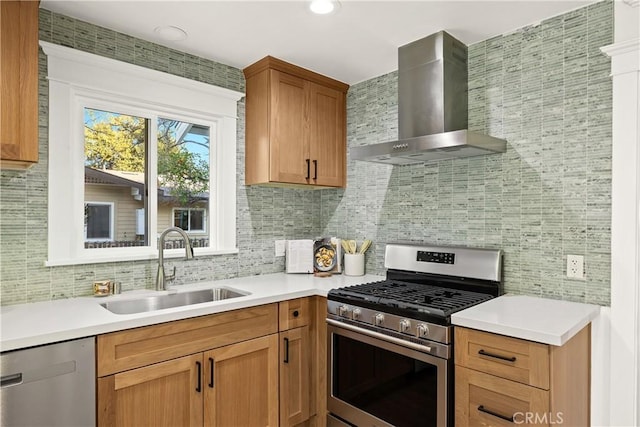 kitchen featuring wall chimney range hood, appliances with stainless steel finishes, tasteful backsplash, and a sink