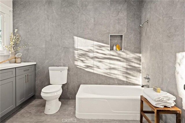 bathroom with toilet, vanity, bathtub / shower combination, and tile walls