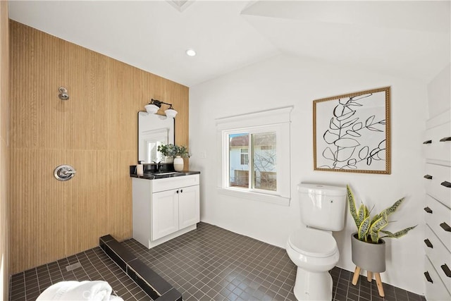 bathroom with lofted ceiling, tile patterned flooring, toilet, vanity, and walk in shower