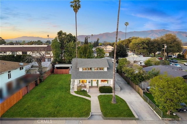 view of front facade with a yard, driveway, fence, and a mountain view