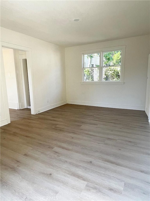 empty room with baseboards and wood finished floors