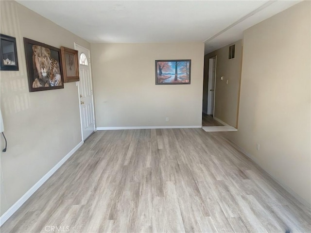 empty room featuring baseboards, visible vents, and light wood-style floors