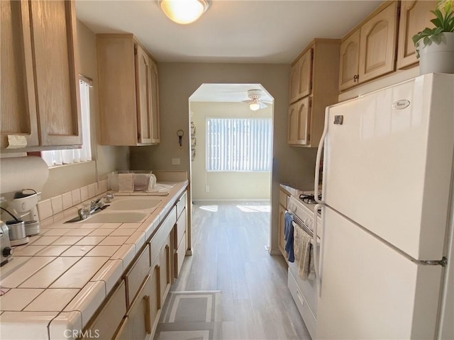kitchen featuring a sink, tile counters, light wood-style floors, light brown cabinets, and white appliances