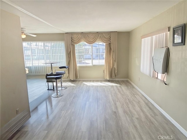 interior space with ceiling fan, wood finished floors, and baseboards