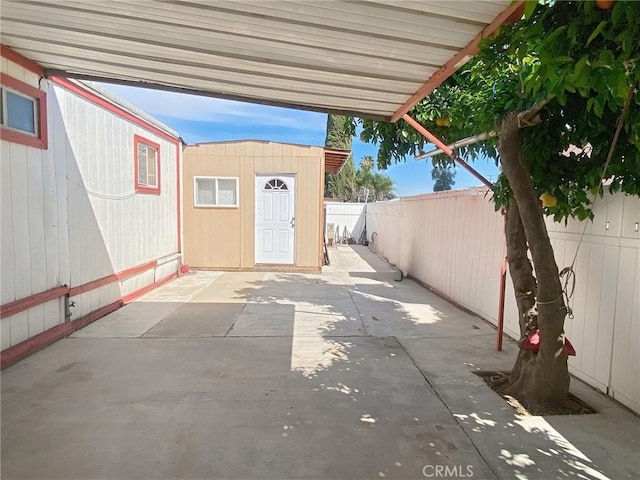 view of patio featuring fence, a shed, and an outbuilding