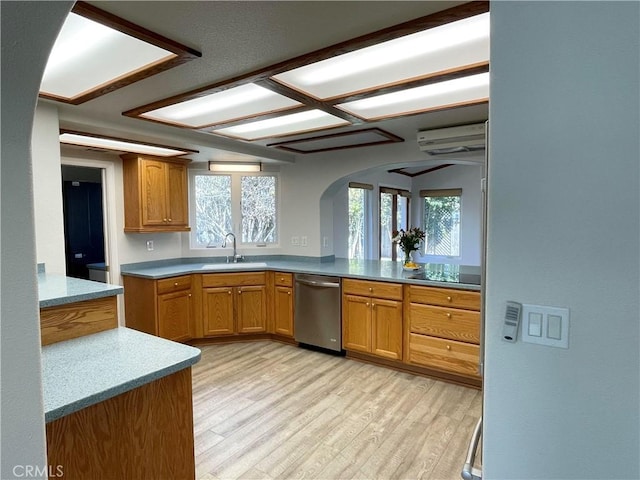 kitchen with light wood-style flooring, a wall unit AC, dishwasher, a sink, and arched walkways