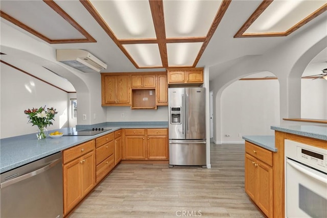 kitchen featuring stainless steel appliances, light wood-style flooring, a ceiling fan, and arched walkways