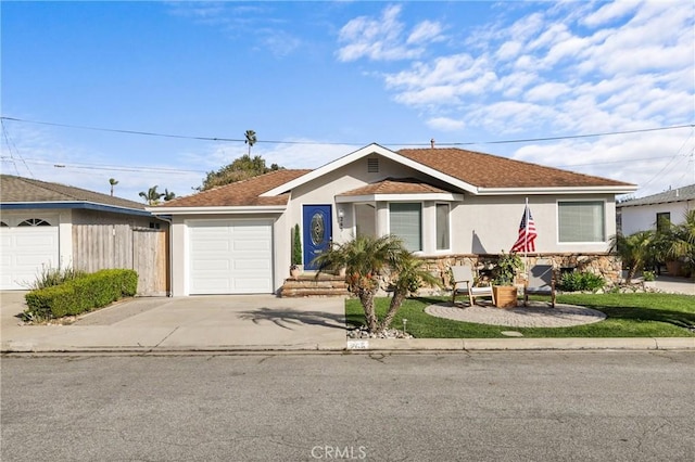 view of front of house with driveway, stucco siding, a garage, and fence