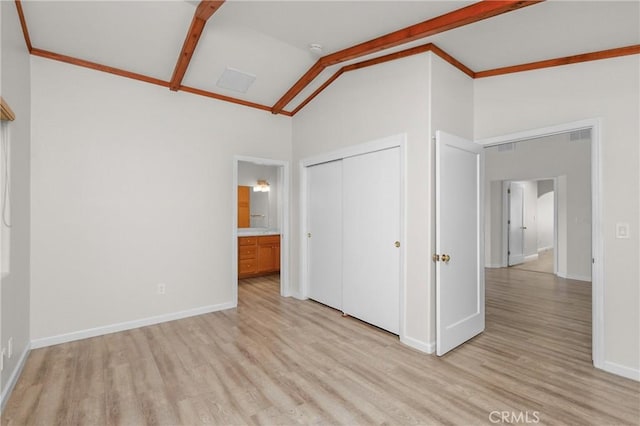 unfurnished bedroom with light wood-style flooring, lofted ceiling with beams, a closet, and baseboards