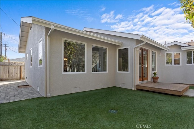 back of house featuring a yard, stucco siding, a deck, and fence
