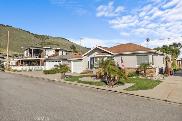 view of front of house featuring stone siding, a mountain view, an attached garage, stucco siding, and driveway