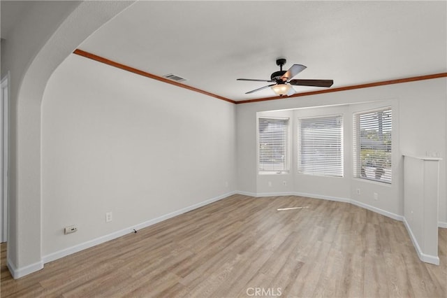 empty room with visible vents, ceiling fan, light wood finished floors, arched walkways, and baseboards