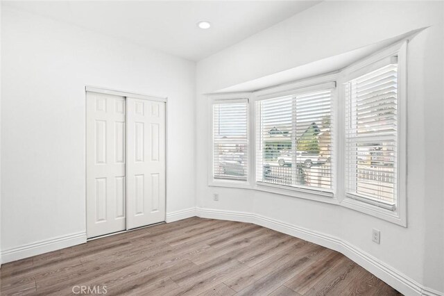 unfurnished bedroom with baseboards, wood finished floors, and a closet