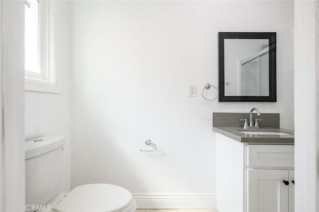 bathroom with toilet, vanity, and baseboards
