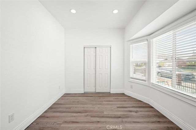 unfurnished bedroom with light wood-style floors, a closet, baseboards, and recessed lighting