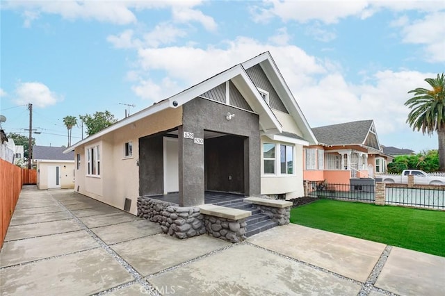 rear view of house featuring a lawn, stucco siding, and fence